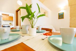 a dining room table with green plates and a plant at Appartamento Rosa Blu PT - MyHo Casa in Torre Canne