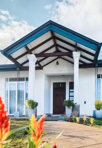 a white house with a blue roof and a porch at Monaara Leisure - NuwaraEliya in Nuwara Eliya