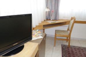 a living room with a television and a desk with a chair at Eichenhof Hotel GbR in Eislingen