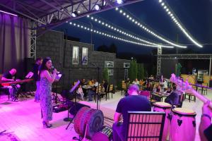 a woman standing on a stage with a microphone at Araks Hotel Complex in Gyumri +66 photos