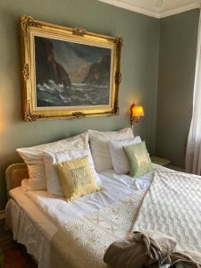 a bedroom with a bed with a painting on the wall at Wedevågs Herrgård in Vedevåg