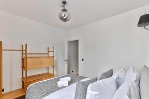 - une chambre blanche avec un lit et une étagère en bois dans l'établissement 97 - Urban Colonnes de Buren, à Paris
