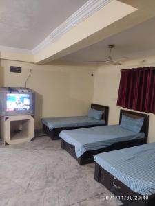 a room with three beds and a tv at Hotel Thakur Shri in Bhopal