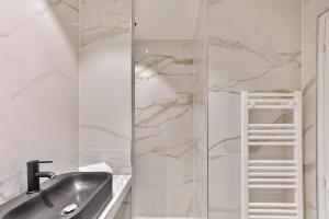 La salle de bains est pourvue d'un lavabo et d'une douche en verre. dans l'établissement 96 - Urban Musée du Louvre, à Paris