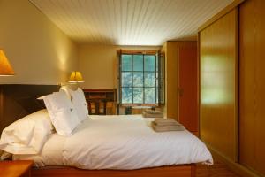 Un dormitorio con una gran cama blanca con ventana. en Finca La Peñiga, en Mazcuerras