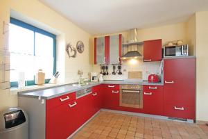 a kitchen with red cabinets and a large window at Ostseetraum Wohnung OG in Wittenbeck