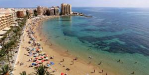 vistas a una playa con gente y al océano en Roda Golf Resort FIT FOX en Murcia