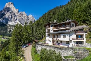 een groot gebouw op een heuvel met bergen op de achtergrond bij Residence Belavista in Corvara in Badia