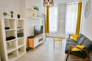 a living room with a couch and a tv at Villa des Ursulines in Valenciennes