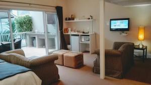 阿爾弗雷德港的住宿－卡微河濱賓館，一间带两把椅子和一台电视的卧室以及一个阳台