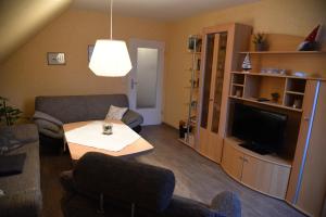 a living room with a couch and a table and a tv at Gästehaus Steffen in Upgant-Schott