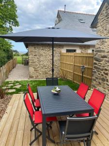 a black table and chairs with an umbrella on a deck at Gîte Bella Laïta in Clohars-Carnoët