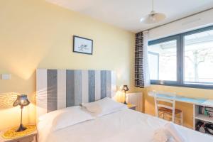- une chambre avec un grand lit blanc et un bureau dans l'établissement Appartement Passereaux - Welkeys, à La Rochelle