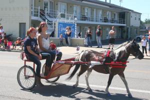 two girls riding a horse drawn carriage down a street at Fountain Inn in Van Wert