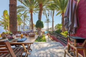 a patio with a table and chairs and palm trees at PHARUS retro beach home New Heated Pool in Maspalomas