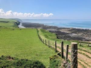 a fence on top of a green field with the ocean at The Nook in Barnstaple