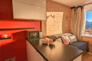 a kitchen and living room with a couch and a table at Cosy studio with balcony at the heart of L'Alpe d'Huez - Welkeys in LʼHuez