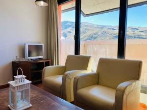 a living room with two chairs and a television at Apartamentos Bluettravel Snow Confort Monte Gorbea in Sierra Nevada