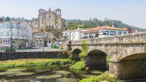 an old stone bridge over a river in a city at Night Day extra in Padrón