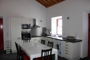 a kitchen with a white table and a white counter top at Adega Do Mirante in São Roque do Pico