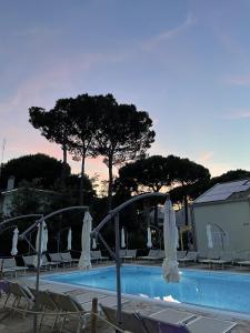 uma piscina com guarda-sóis brancos e cadeiras ao lado em Le Dune Verdi em Lido di Jesolo