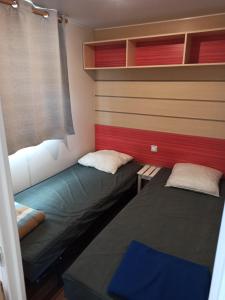 two beds in a room with red and blue at camping le novela in Port-la-Nouvelle