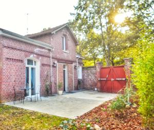 a brick house with a red gate and a patio at Campagne en ville! in Compiègne