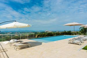 una piscina con sedie e ombrelloni di Resort Orizzonti a SantʼElpidio a Mare