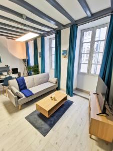 a living room with a couch and a tv at Appartement Ma Douce Charente - Superbe T3 Design et Fonctionnel - Hyper Centre à Saintes in Saintes