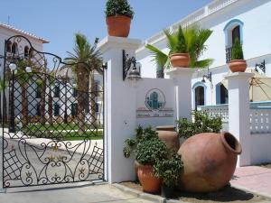 a white house with a gate with potted plants at Hotel Hacienda Don Manuel in Granja de Torrehermosa