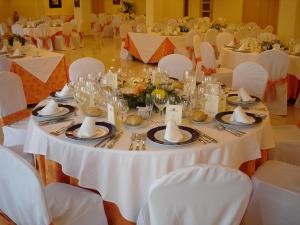 una mesa con mesas blancas y sillas en una habitación en Hotel Hacienda Don Manuel, en Granja de Torrehermosa