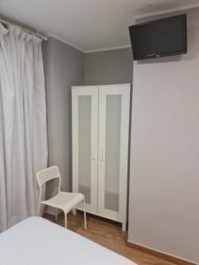 a bedroom with a white bed and a chair at Hostal Fidalgo in Oviedo