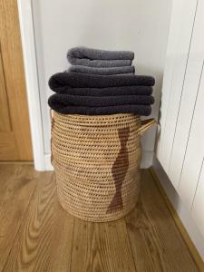 a basket filled with black towels in a room at Cosy Cotswolds Self-Contained One Bedroom Cottage in Chipping Norton