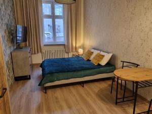 1 dormitorio con cama, mesa y ventana en Apartamenty 21 Stare Miasto en Szczecin