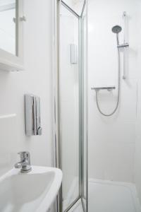 a white bathroom with a shower and a sink at TLK Apartments & Hotel - Beckenham Junction in London +25 photos