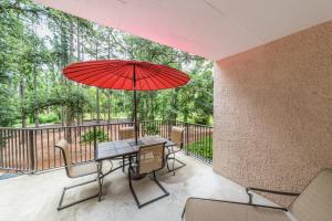 a patio with a table and a red umbrella at Village House 102 in Hilton Head Island