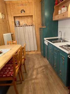 cocina con armarios verdes y mesa de madera en Casa Mia Fiemme, en Carano