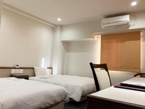 a hotel room with two beds and a desk with a computer at Hotel Ascent Hamamatsu in Hamamatsu