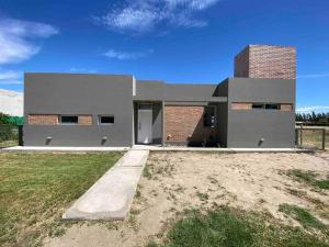 a house in a field with a grass yard at Casa con pileta y parrilla en barrio privado, 2 dormitorios in General Roca