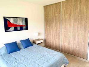 a bedroom with a blue bed and a wooden closet at Casa con pileta y parrilla en barrio privado, 2 dormitorios in General Roca