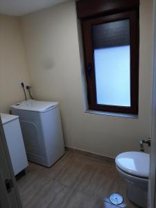 a bathroom with a toilet and a sink and a window at Piso amplio y reformado para grupos in Felechosa
