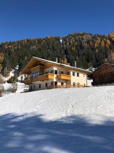 a house on top of a snow covered hill at Apartments Oberhollenzer in Braies