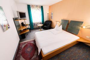 ein Hotelzimmer mit einem Bett und einem Stuhl in der Unterkunft Hotel Residenz in Schnelldorf