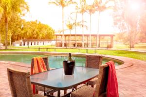 a table with chairs next to a swimming pool at Noosa North Shore Retreat in Noosa North Shore