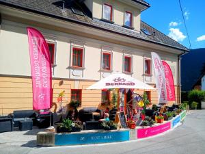 Garni Hotel Bovec في بوفيك: مبنى فيه مظله وطاولات وكراسي