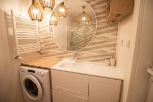 a bathroom with a sink and a mirror and a washing machine at Apartament Dar Pomorza 20m do Plaży Ustronie Apartments in Ustronie Morskie