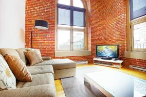 a living room with a couch and a tv in a brick wall at La Casa St-Jean - OLD QUEBEC in Quebec City