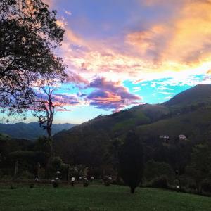 einen Sonnenuntergang auf einem Feld mit Bergen im Hintergrund in der Unterkunft Paraíso da Mantiqueira são Francisco Xavier sp in São Francisco Xavier