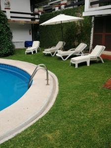 a swimming pool with lounge chairs and an umbrella at Casa Dalinda in Valle de Bravo
