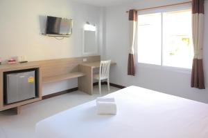 a bedroom with a bed and a desk and a tv at Pueanjai Resort and Restaurant in Chumphon